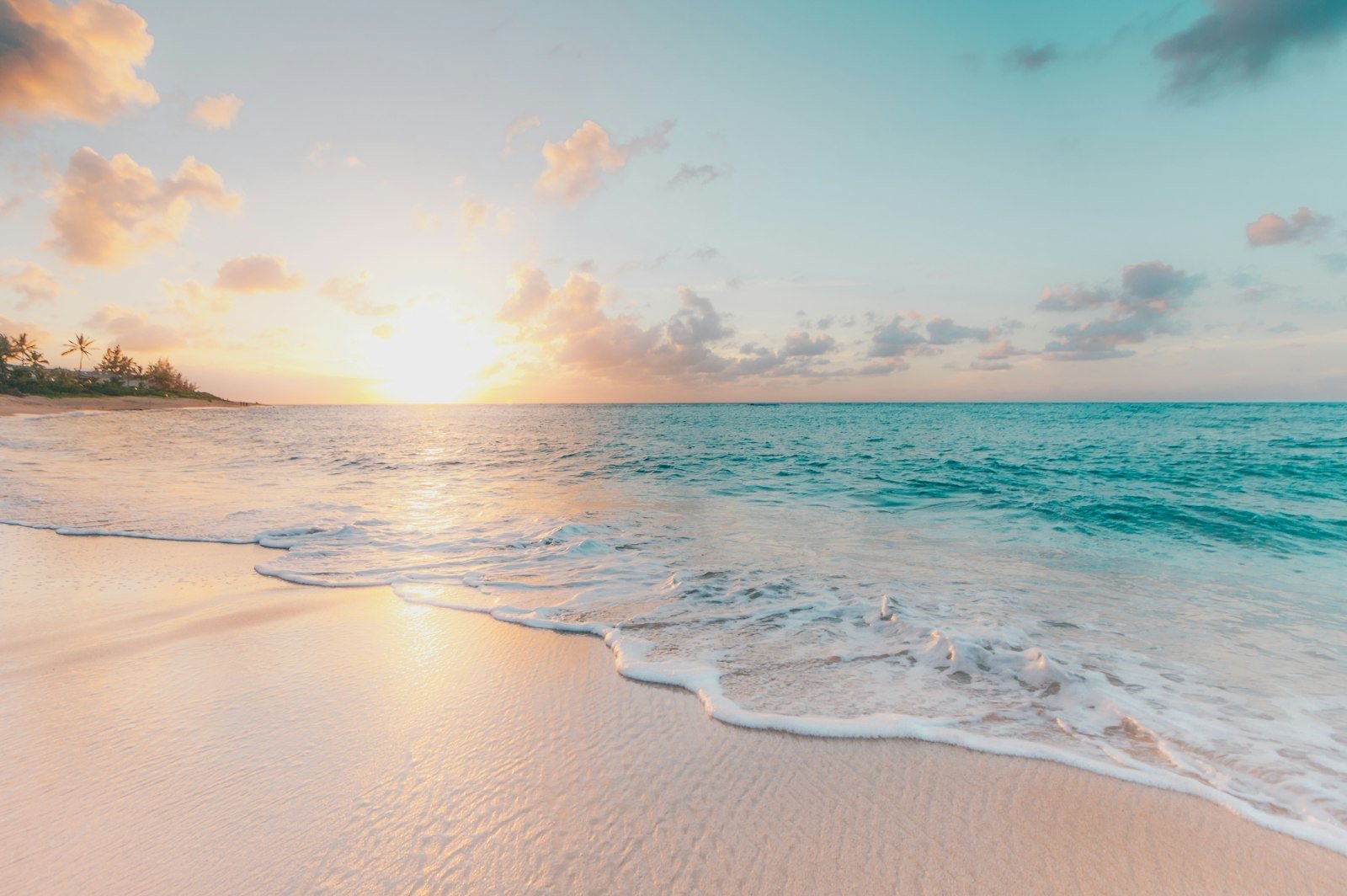 Turquoise sea meeting a white-sand beach at sunset