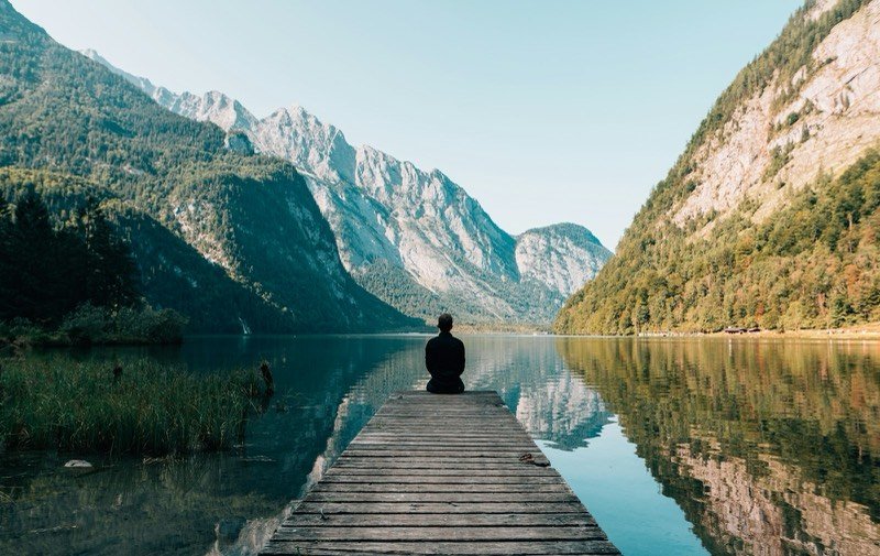Traveler sitting on a dock over an alpine lake