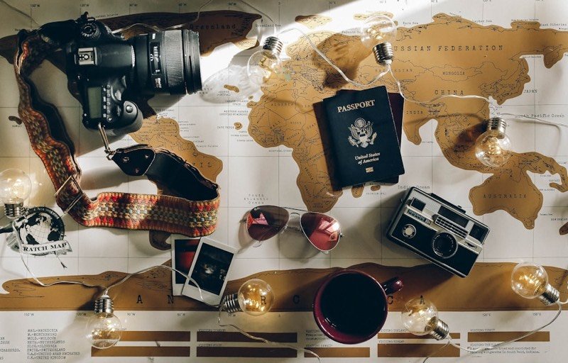 Passport and camera laid over a world map — trip paperwork ready